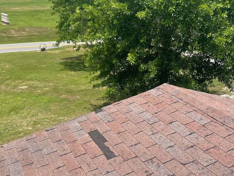 Close-up of worn, weathered three-tab asphalt shingles with mismatched patches during a Hot Springs roof inspection