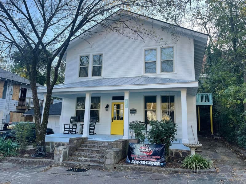 White two-story Hot Springs home with a new gray metal porch roof and a Speedy Gonzalez Roofing yard banner out front