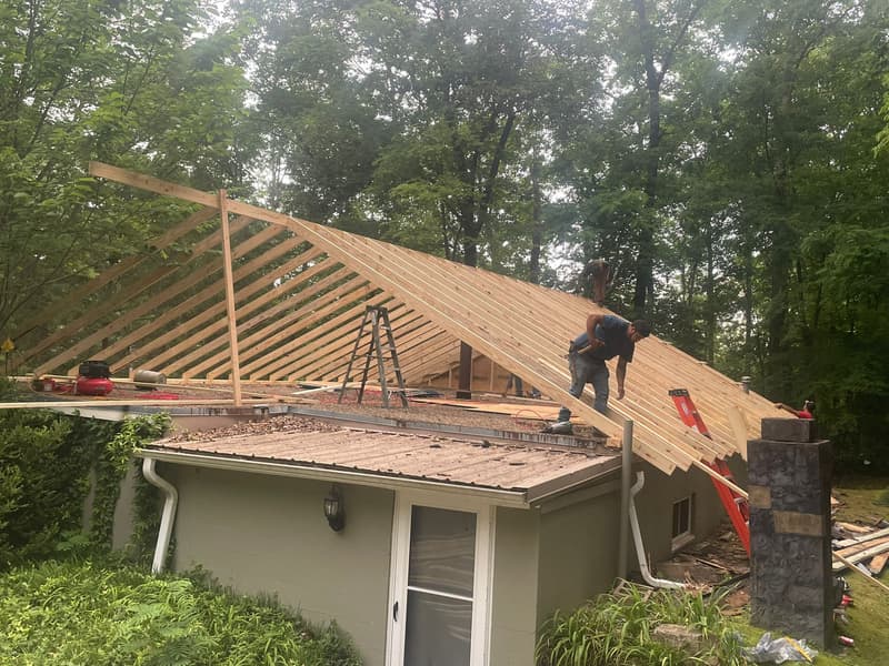A Speedy Gonzalez Roofing crew framing new roof rafters over an older low-slope roof on a Hot Springs home
