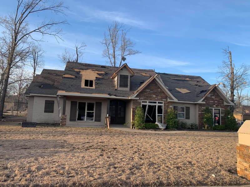 Central Arkansas home with shingles torn off and decking exposed after a severe storm